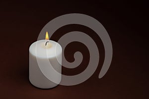 One whiteÃÂ candleÃÂ flameÃÂ burningÃÂ onÃÂ dark backgroundÃÂ withÃÂ copyÃÂ space forÃÂ text